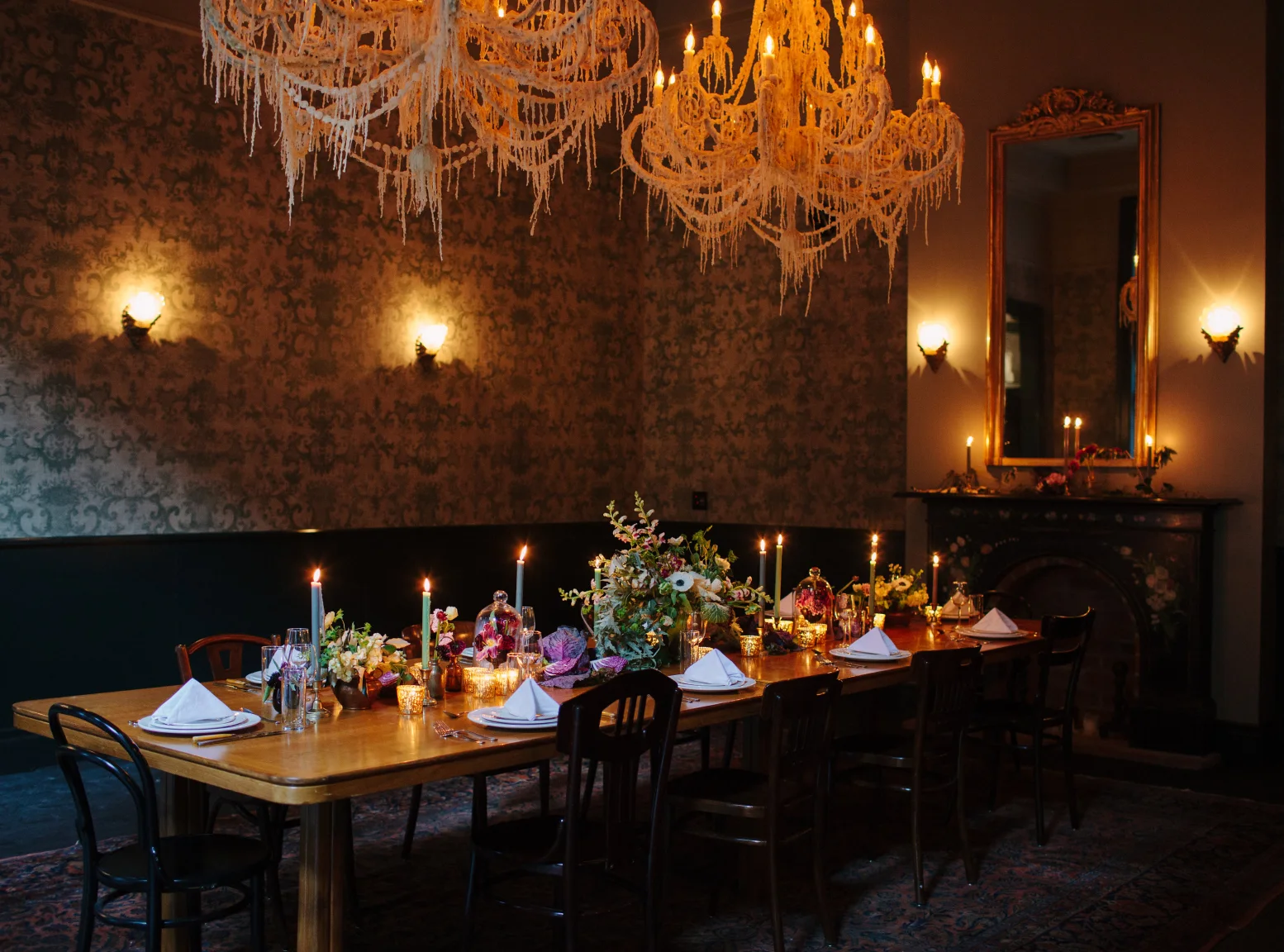 Dramatic setting in a hotel wedding venue with moody lighting, ornate chandeliers, and a fully set dinner table