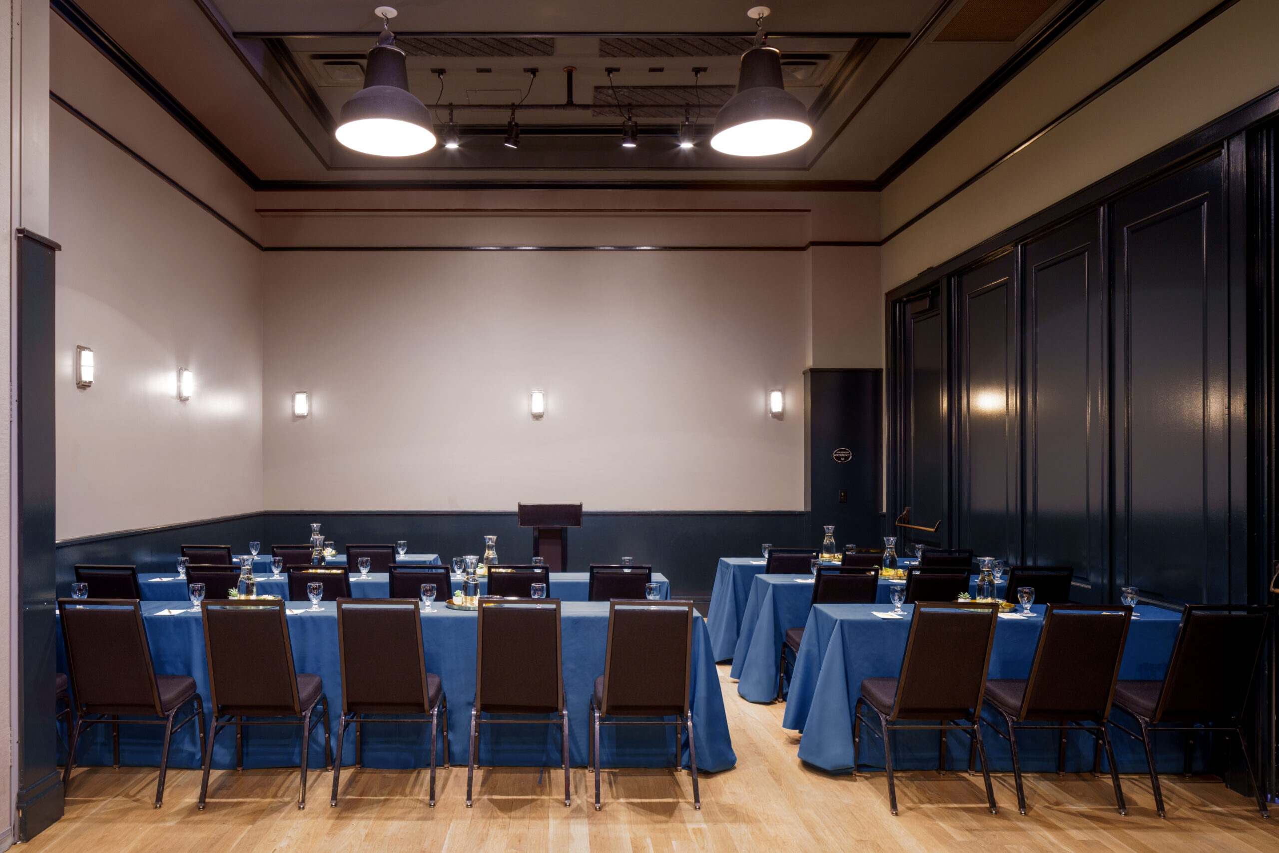 Organized conference room with dark blue tables set up theater style and a central podium