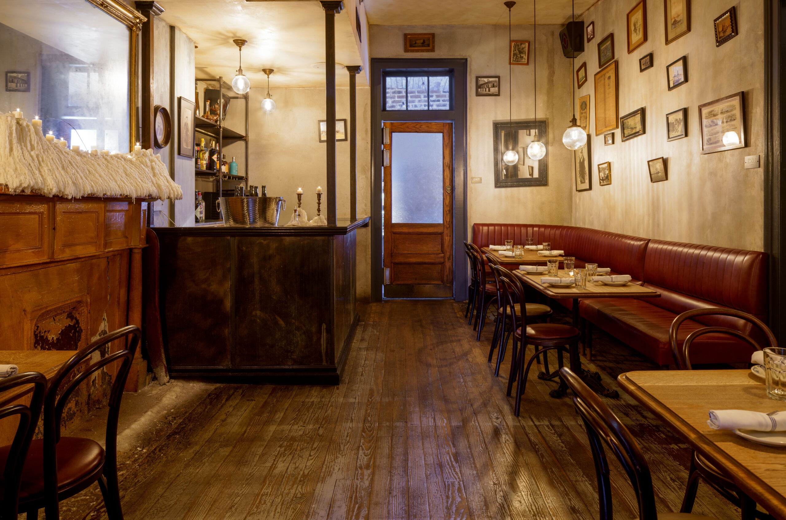 Warm, historic dining room featuring deep red leather booth seating and a dark wood candlelit bar
