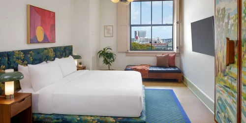 Professional shot of a king bed with white sheets and stylized nightstands typical of boutique hotels new orleans