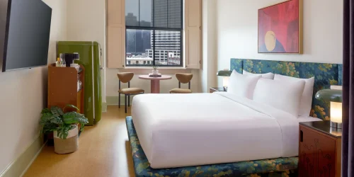 Stylish lodging featuring a queen bed, green SMEG fridge, and modern lighting