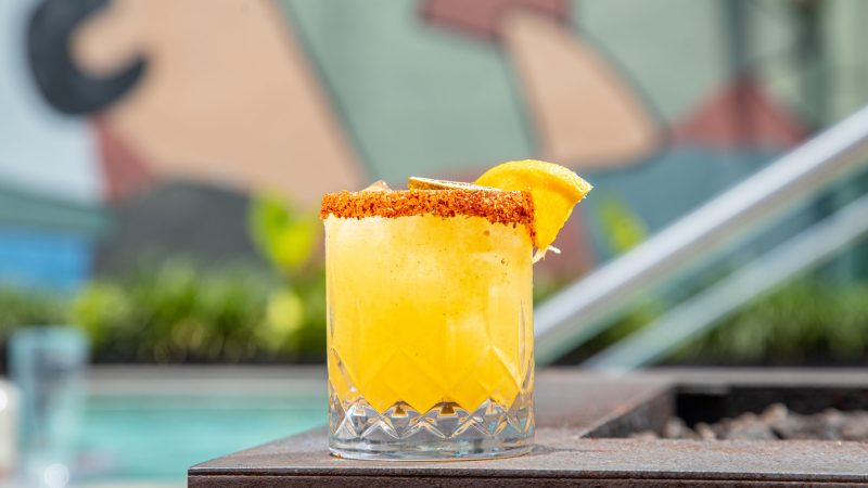 Vibrant yellow cocktail with a spiced rim served poolside at New Orleans hotels with rooftop pools
