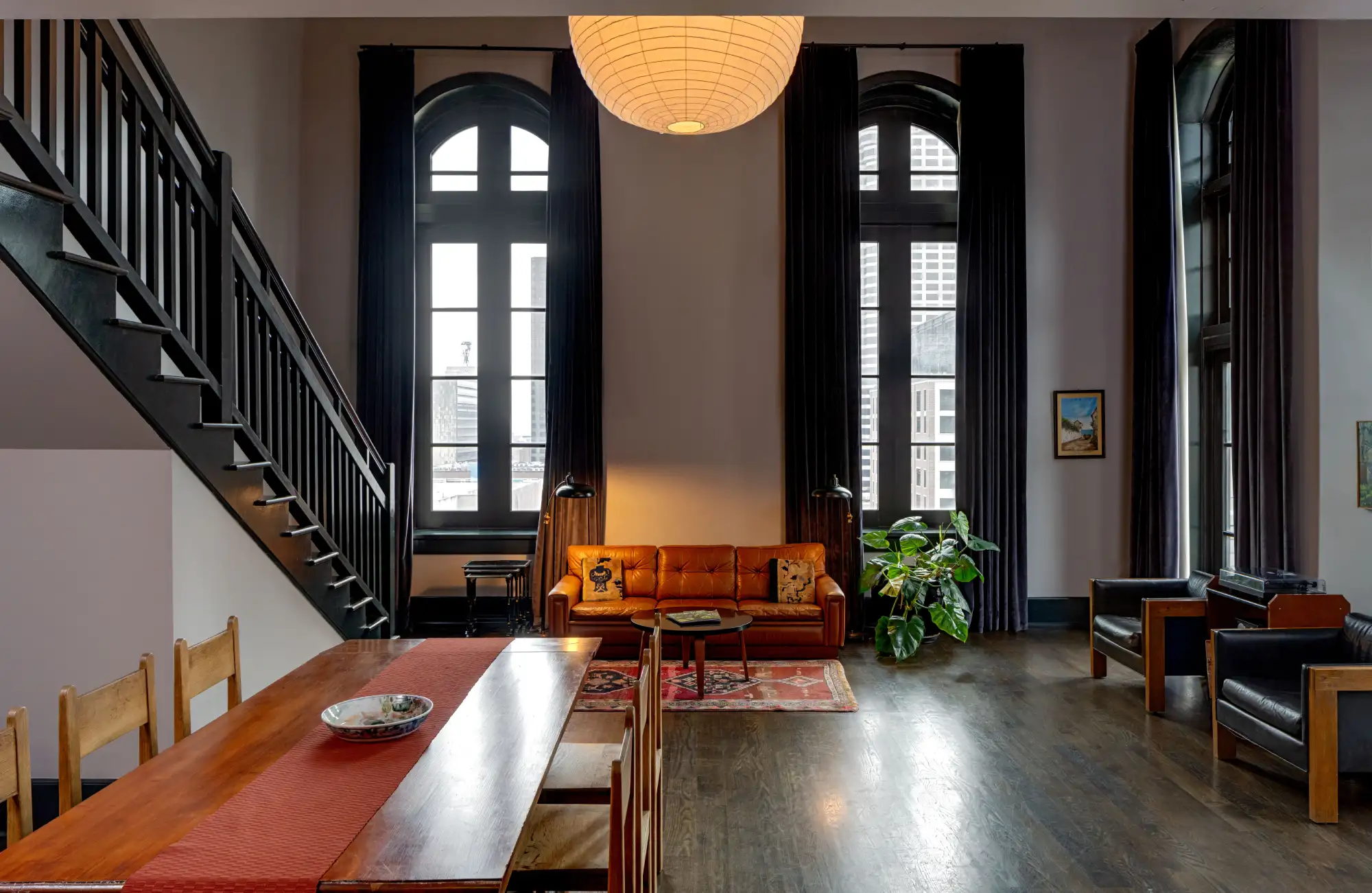 Professional shot of a spacious, modern hotel suite in New Orleans with loft stairs and high windows