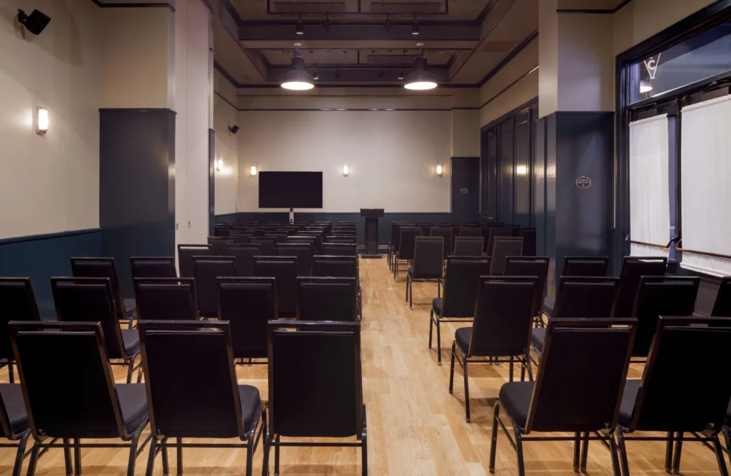 a room filled with black chairs and a projector screen