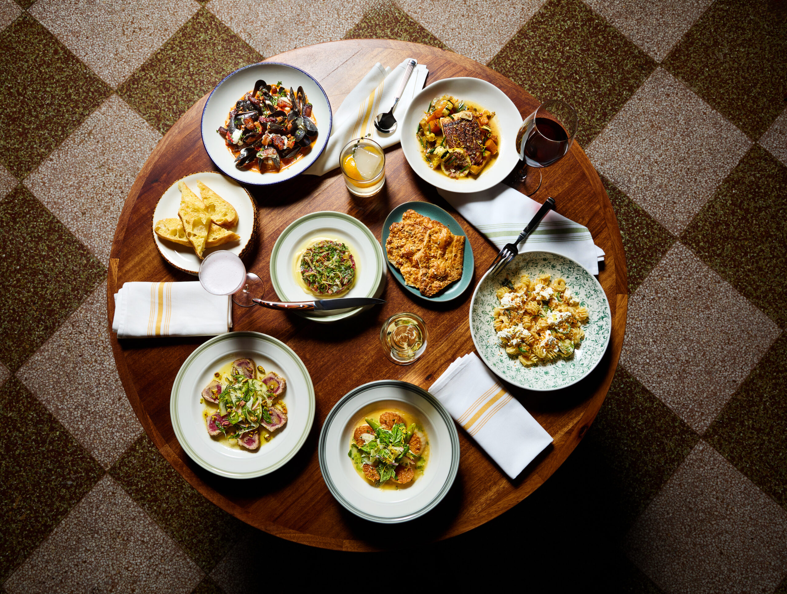 Professional shot of a round table displaying several gourmet dinner plates and drinks