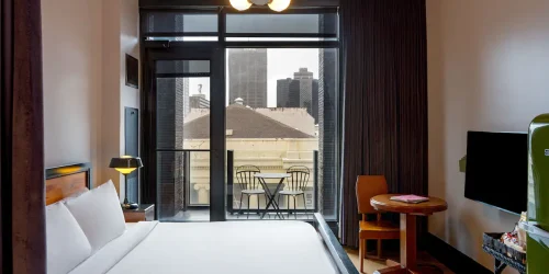 Modern hotel suite in New Orleans featuring a comfortable bed and a private balcony with city views