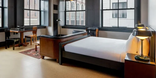 Detailed view of a vintage-modern hotel suite featuring dark furniture and large industrial windows