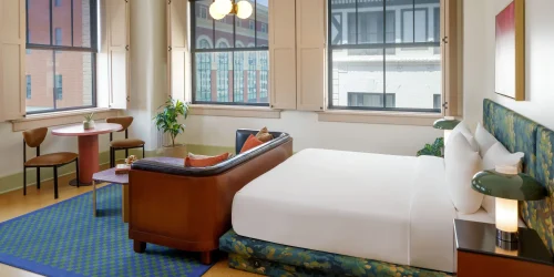 Detailed view of a vintage-modern hotel suite featuring dark furniture and large industrial windows