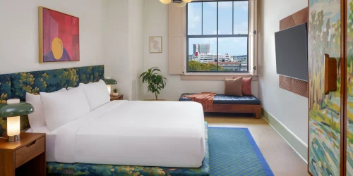 Professional shot of a king bed with white sheets and stylized nightstands typical of boutique hotels new orleans