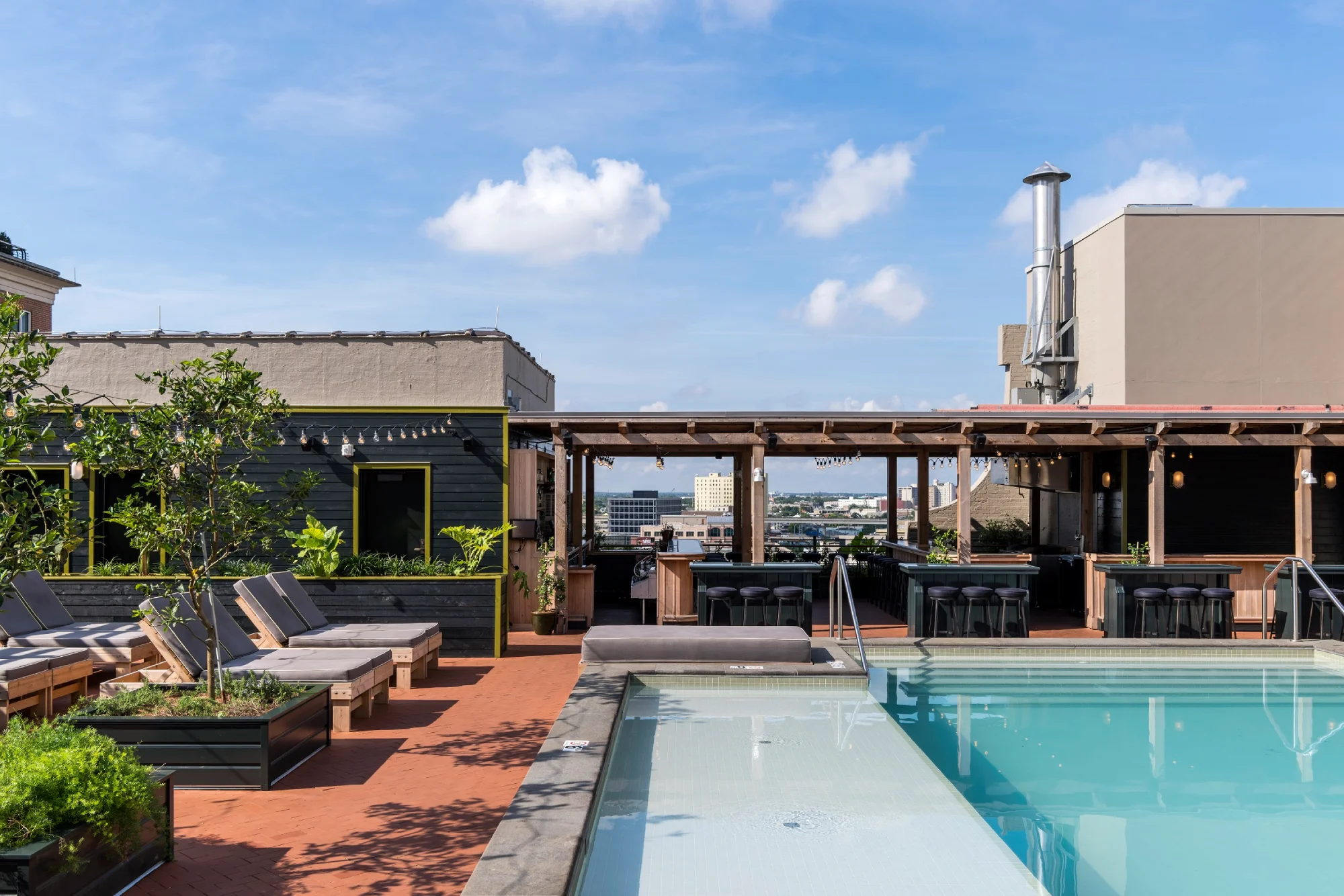 a swimming pool with lounge chairs and tables next to it