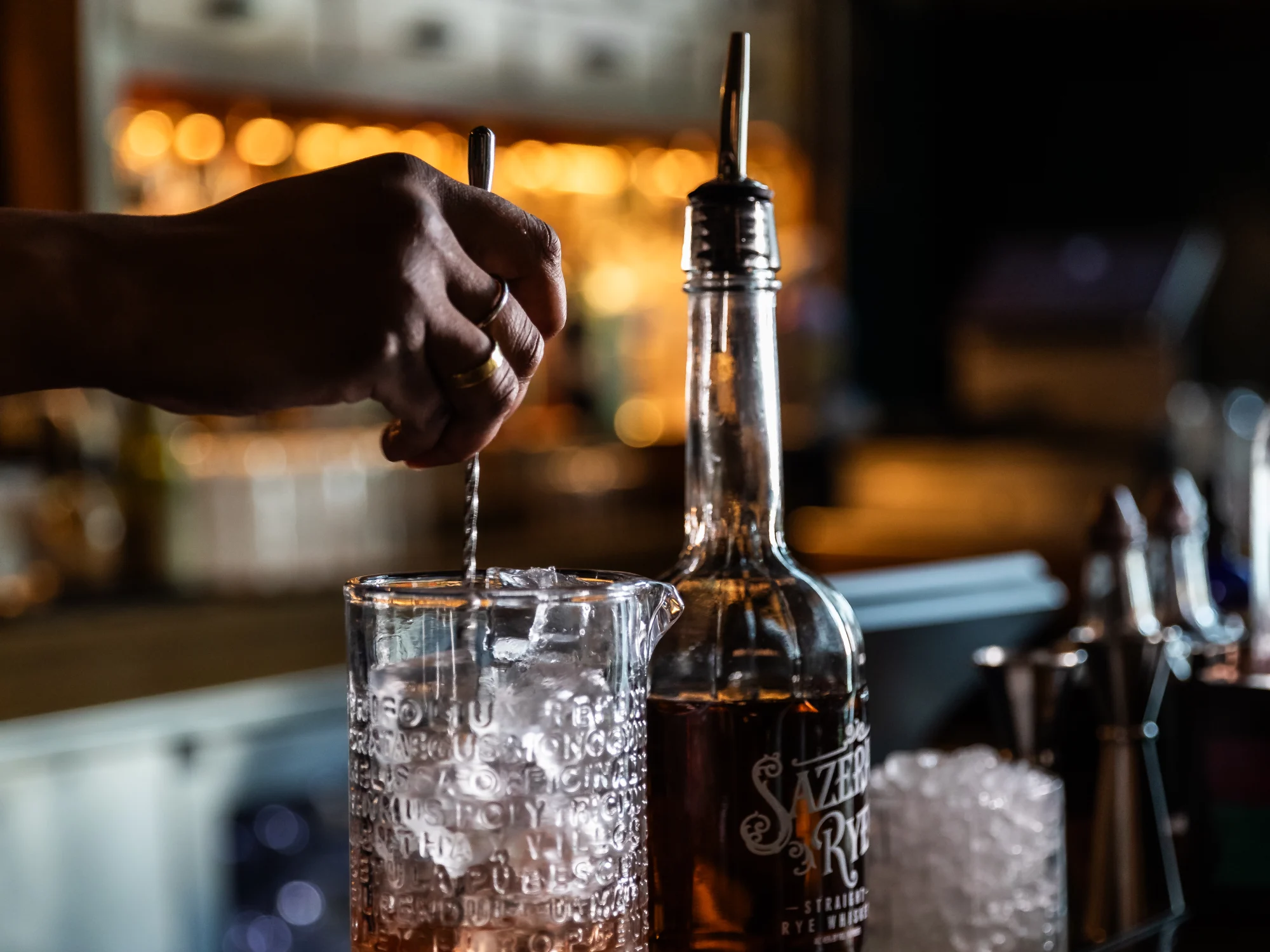 Professional shot of a bartender stirring a Sazerac cocktail at a stylish New Orleans bar