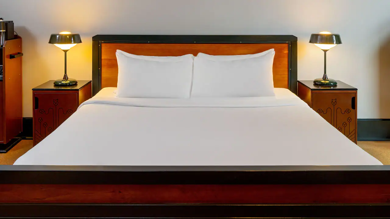 a bed with white sheets and pillows in a room