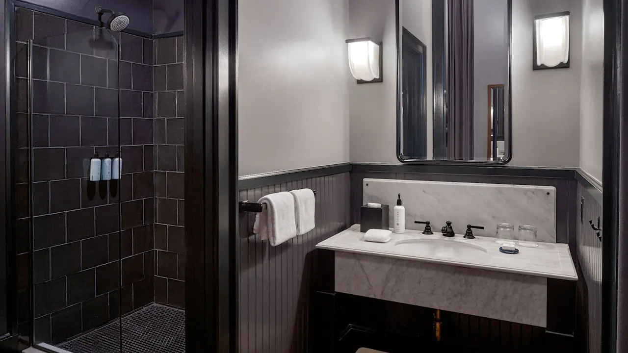 a bathroom with a sink, mirror, and shower stall