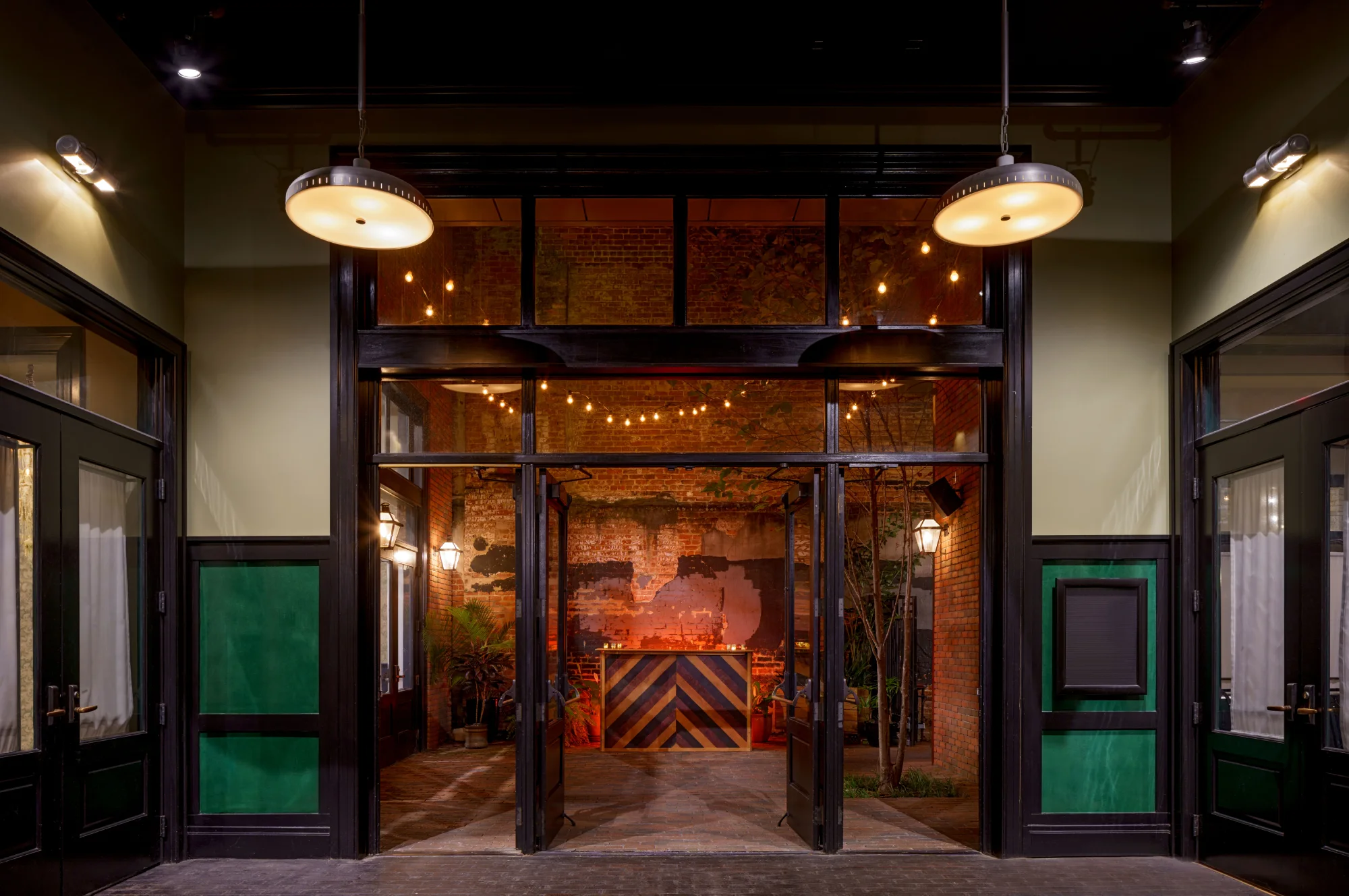 Stylish entrance to a bar venue in the French Quarter showing open doors and a wooden chevron counter