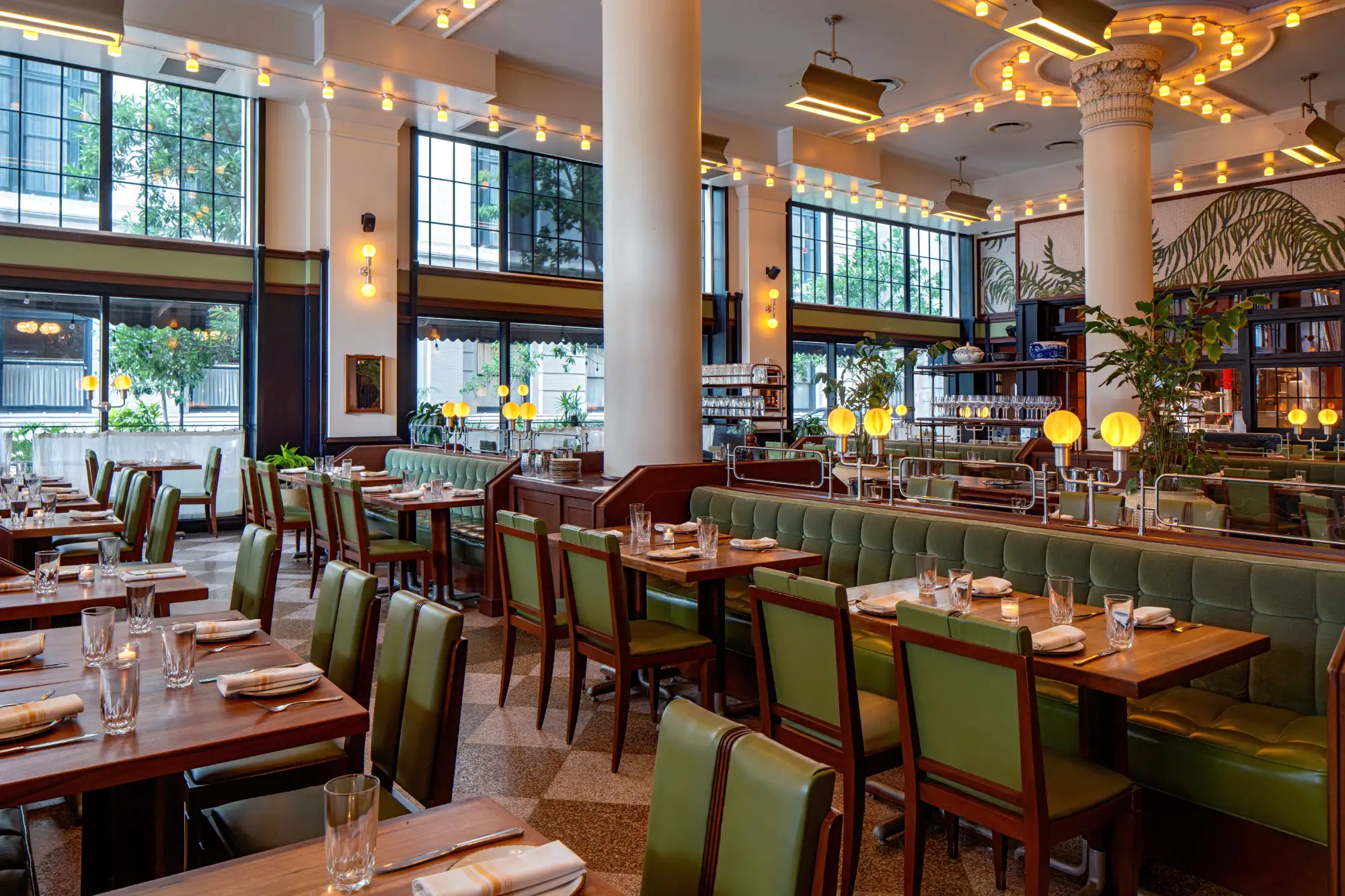 Spacious, brightly lit restaurant dining room featuring long green leather booths and wooden tables