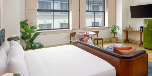 Professional shot of a modern hotel suite with leather sofa and large city view window